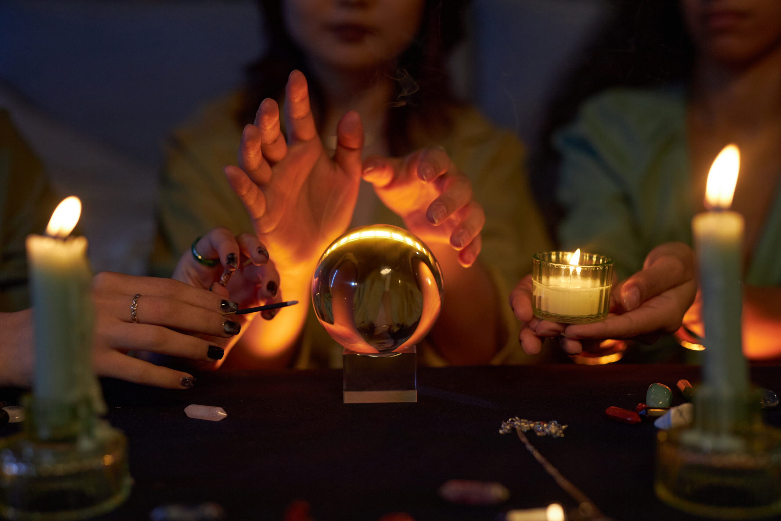 Medium closeup of three young girls practicing fortune telling with use of crystal ball during magic themed party